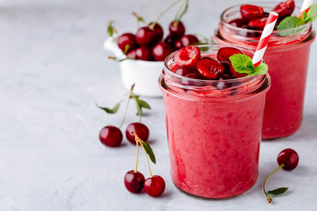Cherry smoothie in glass with mint leaves and fresh berries