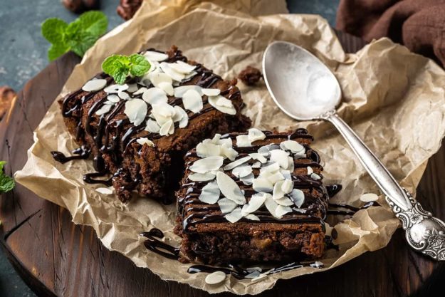 Chocolate brownie cake, dessert with nuts on dark background, directly above, flat lay