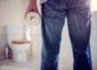 Man holding toilet paper roll in bathroom
