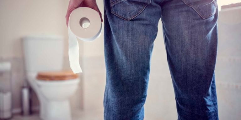 Man holding toilet paper roll in bathroom