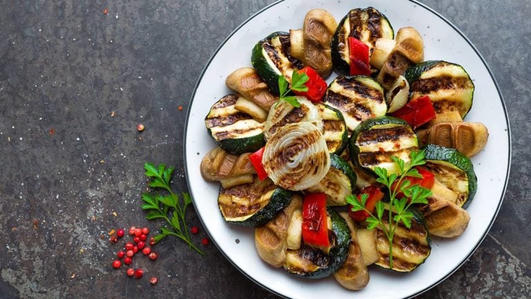 Salad with grilled vegetables and mushrooms. Vegetable salad with grilled champignons. Grilled salad on plate