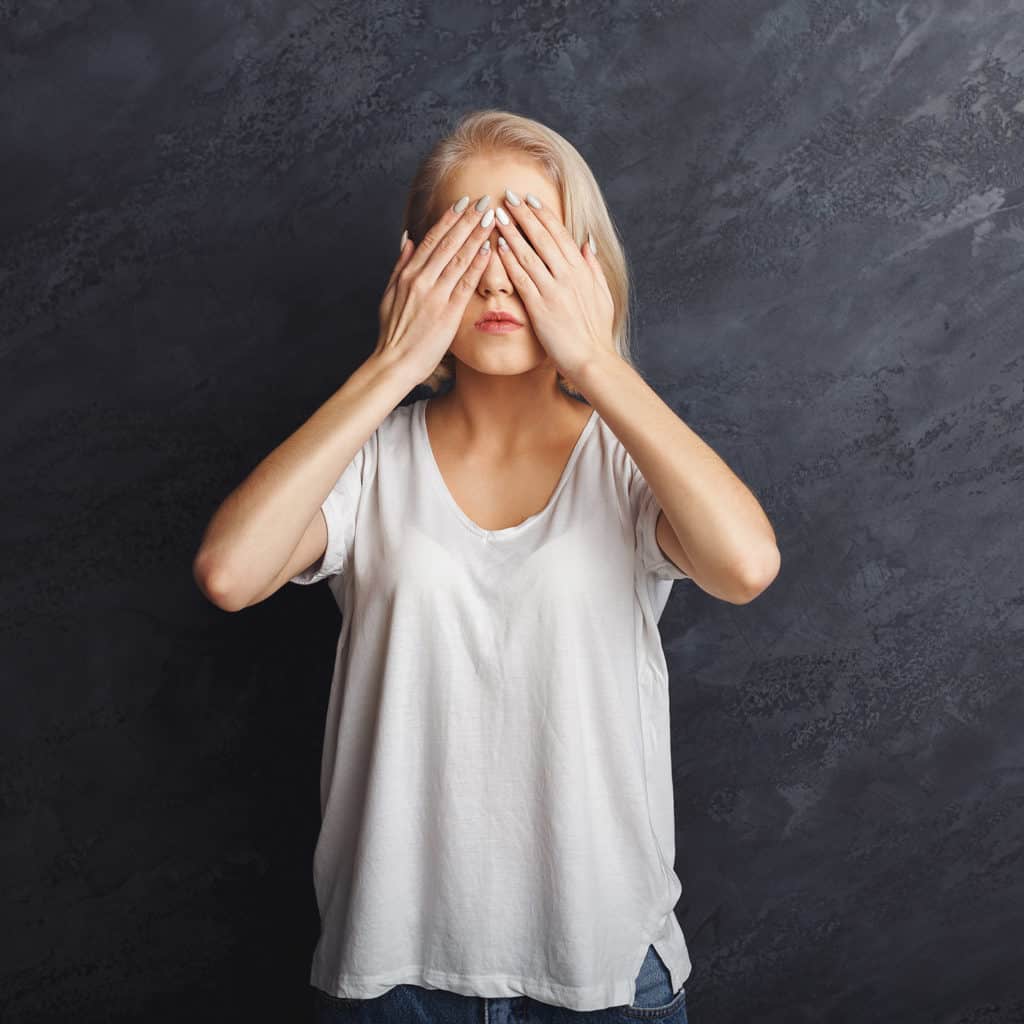 Scared woman covering eyes with hands, see no evil