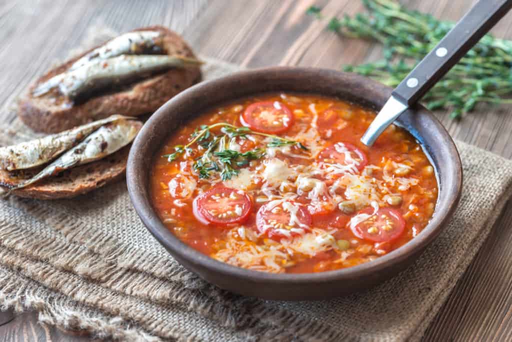 Portion of green lentil tomato soup with toasts