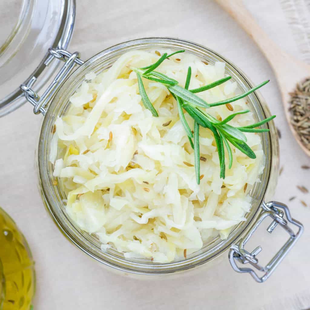 Homemade sauerkraut with cumin in a glass jar, top view, square