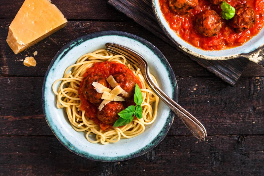 Pasta with meatballs and spicy marinara sauce and cheese, top view, rustic style.