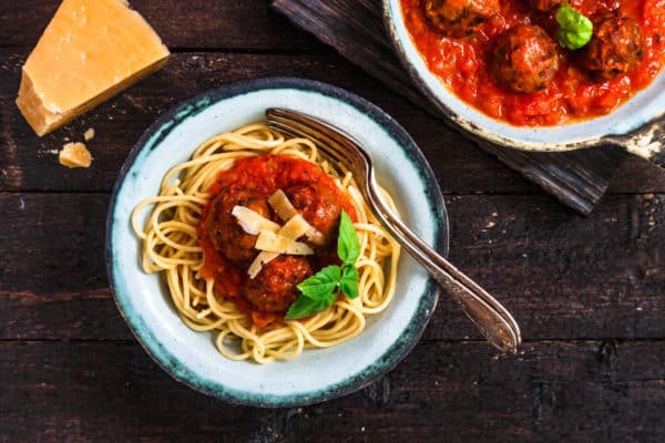 Pasta with meatballs and spicy marinara sauce and cheese, top view, rustic style.